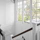 Freshly painted staircase in Brisbane home with white panelled walls, timber handrail and large windows